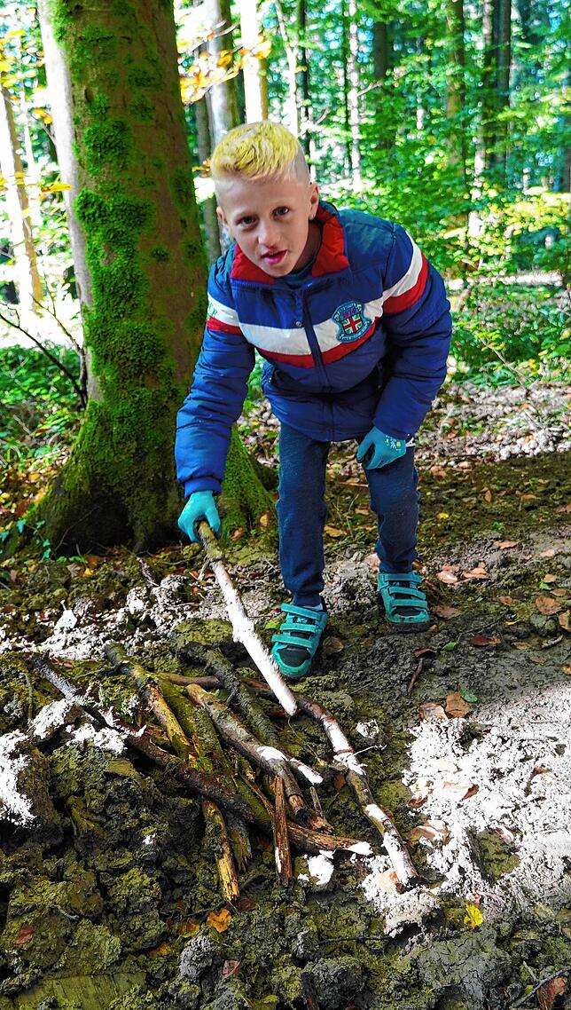 Der neunjährige Nils sammelt Holzstücke zur Stabilisierung des Wegs.