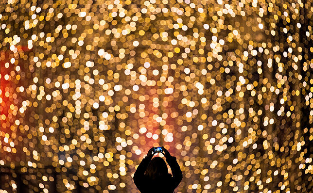 Eine Frau fotografiert die Fassade des mit Lichterketten weihnachtlich geschmückten Einkaufszentrums &ldquo;Hamburger Meile&bdquo;.