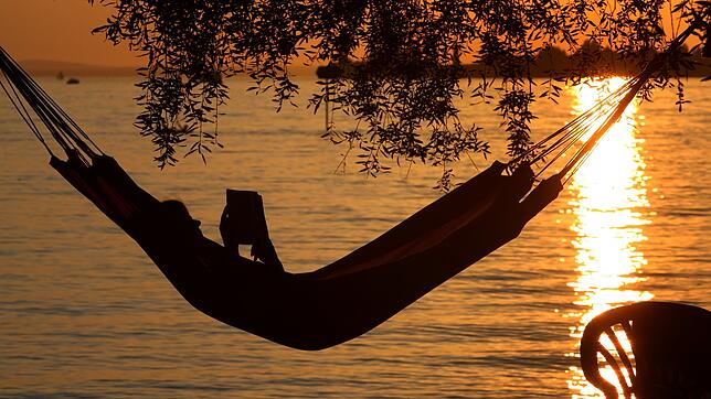 Eine Frau liest in einer Hängematte am Bodensee in Lindau ein Buch.