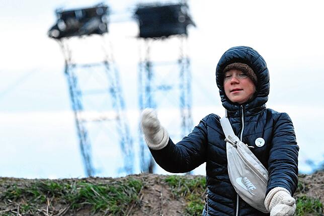 Die Klimaaktivistin Greta Thunberg steht mit anderen Aktivisten zwischen Keyenberg und Lützerath unter Polizeibewachung am Tagebau und ...