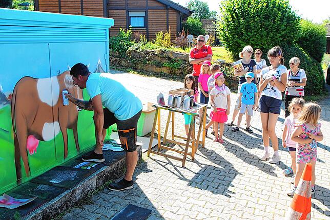 Hingerissen verfolgen Kinder wie Erwachsene wie auf der Trafostation durch die Hand von Jochen Laufer eine Kuh mit Bergenlandschaft im ...
