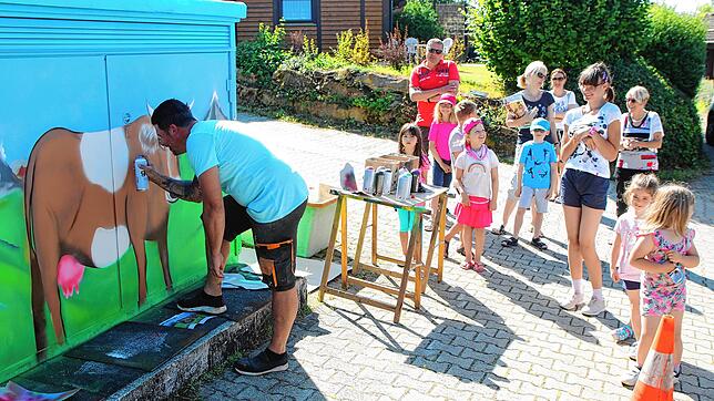 Hingerissen verfolgen Kinder wie Erwachsene wie auf der Trafostation durch die Hand von Jochen Laufer eine Kuh mit Bergenlandschaft im ...