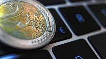 Eine Zwei-Euro-Münze liegt auf der Tastatur eines Laptops. Die Notenbanken im Euroland wollen einen digitalen Zwilling des Euro-Bargelds ...