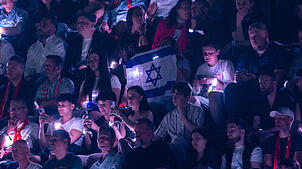 Zuschauer in Basel halten israelische Fahnen beim Auftritt von Yuval Raphael beim zweiten Halbfinale des ESC 2025 hoch. Um die Teilnahme ...
