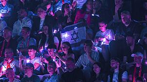Zuschauer in Basel halten israelische Fahnen beim Auftritt von Yuval Raphael beim zweiten Halbfinale des ESC 2025 hoch. Um die Teilnahme ...