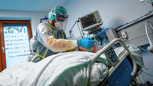 Ein Intensivpfleger arbeitet in Schutzausrüstung an einem Corona-Patienten.