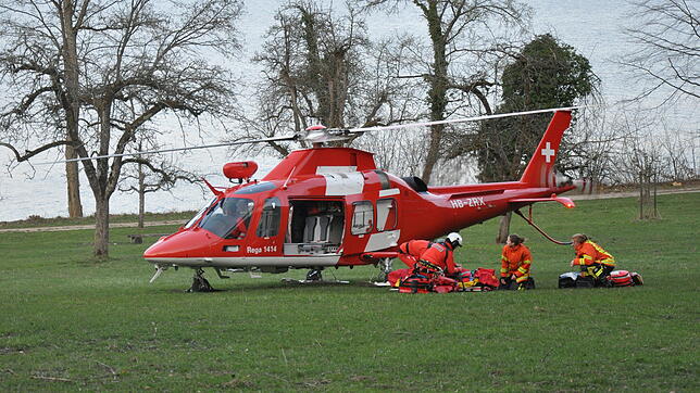 Helfer des Roten Kreuzes und die Besatzung eines Schweizer Rettungshubschraubers versorgen bei einer Zwischenlandung bei Bodman den ...