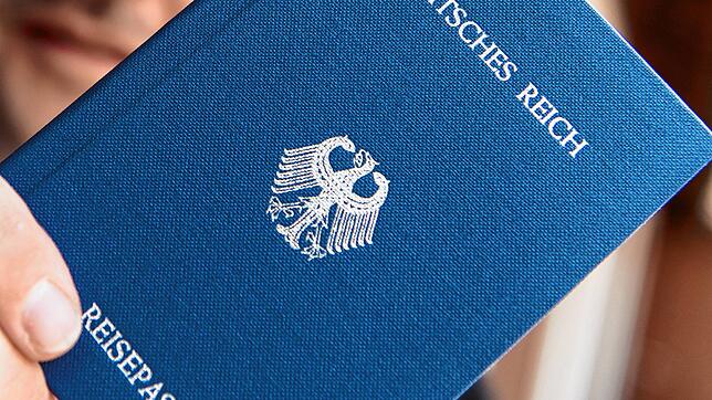 Ein Mann hält ein Heft mit dem Aufdruck &bdquo;Deutsches Reich Reisepass&ldquo; in der Hand. Ein mutmaßlicher Reichsbürger soll mehrere ...