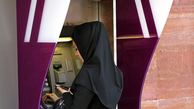 epa05557002 An Iranian woman uses an automated teller machine (ATM) of Bank Eqtesad Novin Iran, in Tehran, Iran, 26 September 2016. ...