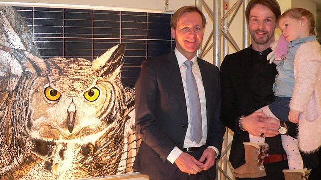 Ralph Schulz mit Tochter Mira neben Laudator Philipp Frank. Links daneben das Bild "Eagle Owl" mit Acryl auf Solar Paneel. Bild: ...