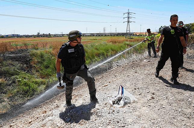 Mitglieder der israelischen Sicherheitskräfte am Einschusspunkt einer Luftrakete am Gaza Streifen nahe des israelischen Ben Gurion ...