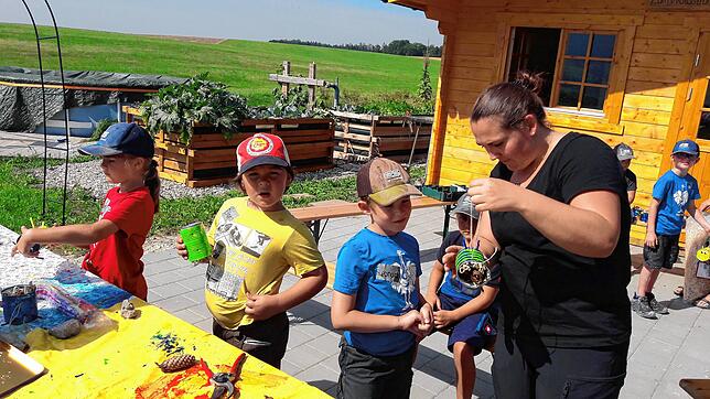 Luisa Rieder zeigt den Kindern, von links Maren, Eliano, Leonhard und Nina, wie sie aus einer Büchse ein Insektenhotel erstellen können.