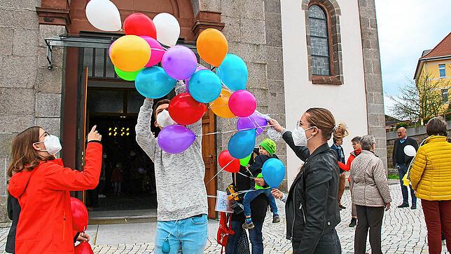 Eine bunte Überraschung für kleine Pfingstgottesdienst-Besucher: Draußen vor der Kirchentüre beschenken in Schönwald die Ministranten ...