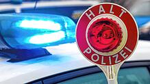 Ein Polizist hält eine Polizeikelle für eine Kontrolle auf einem Parkplatz an der Autobahn 72.