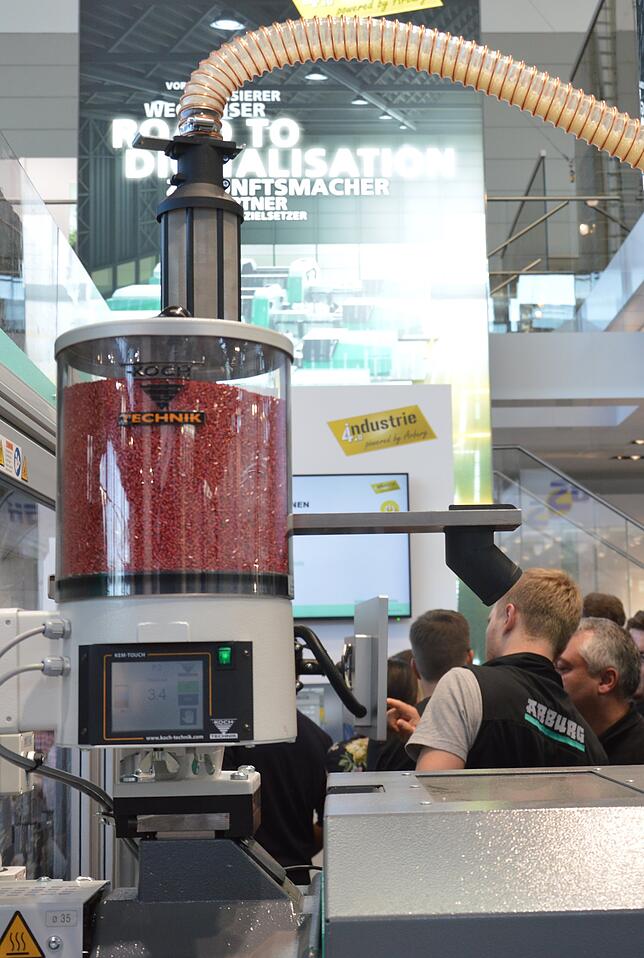 Aus rotem Kunststoffgranulat wird mit Hilfe einer Spritzgussmaschine der Rahmen für eine  Wasserwaage.