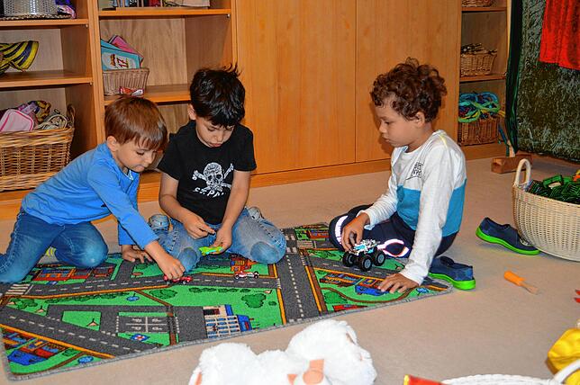 Sie sind froh, den Kindergarten in Leimbach besuchen zu dürfen: Linus, Malik und Diago beim Spielen mit Autos auf dem Verkehrs-Spielteppich.