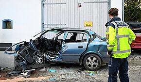 Ein Polizist steht an der Unfallstelle. Eine 49-Jährige gerät mit ihrem Auto in einer Kurve ins Schleudern und prallt gegen eine Wand. ...