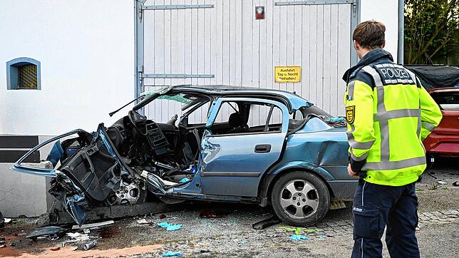 Ein Polizist steht an der Unfallstelle. Eine 49-Jährige gerät mit ihrem Auto in einer Kurve ins Schleudern und prallt gegen eine Wand. ...