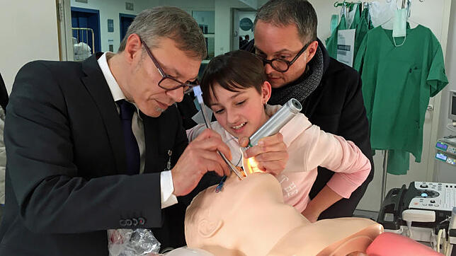 Ein Arzt zeigt einer jungen Besucherin die Intubation an einer Puppe.