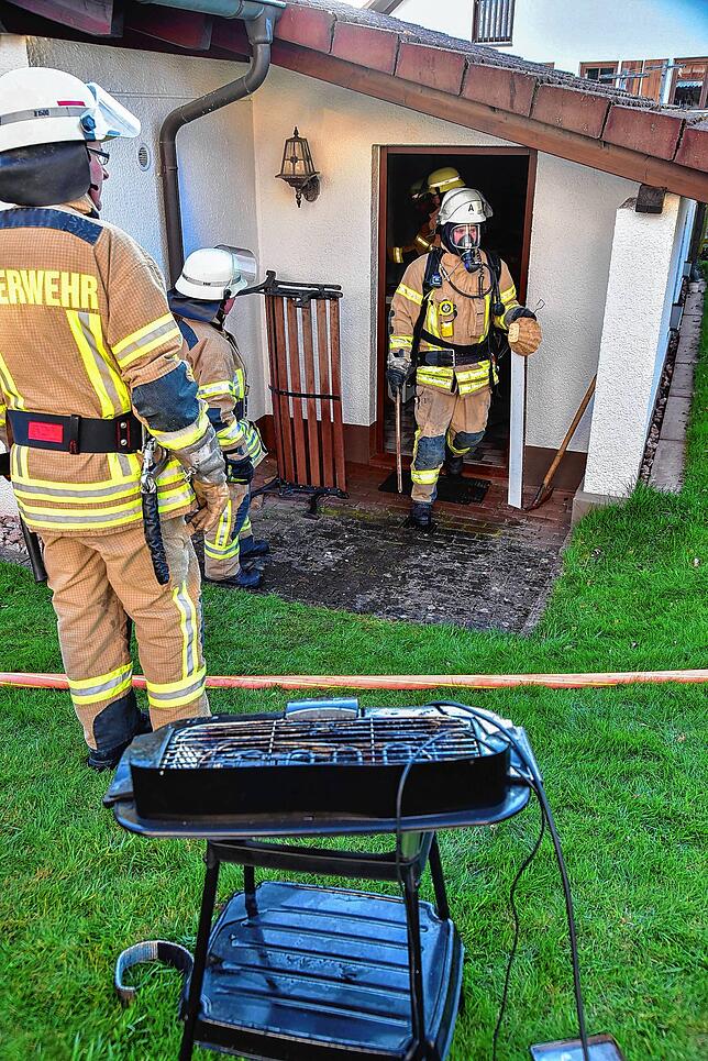 Feuerwehrleute räumen Untensilien aus dem Raum hinter einer Garage in Obereschach.