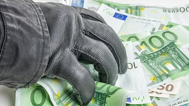 Dieb mit Lederhandschuh greift nach Geldscheinen.