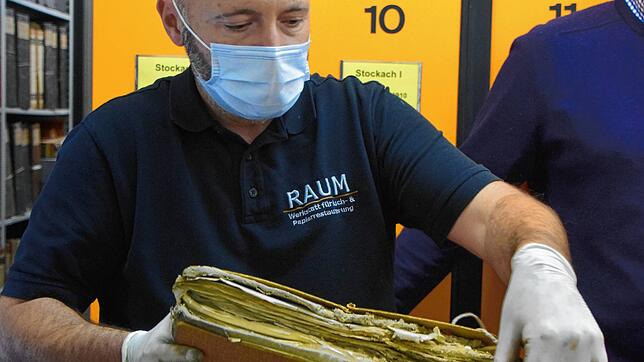 Matthias Raum löst vorsichtig die Schnüre einer Mappe.