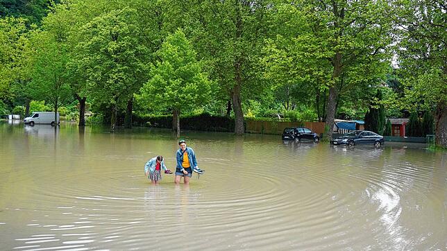 Seelandschaft in der Waldshuter Schmittenau: Diese beiden waten auf der Straße, die zum Schwimmbad führt, durch kniehohes, trübes ...