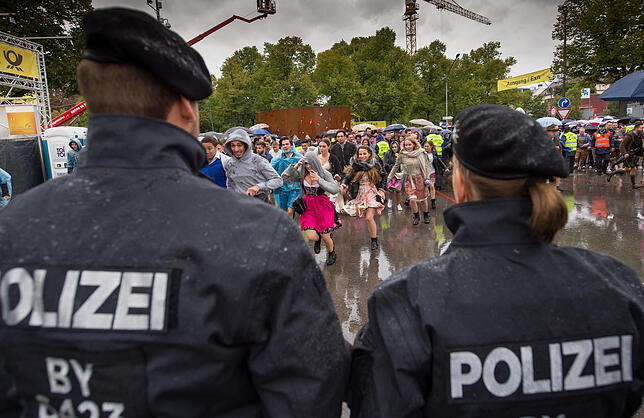 Junge Besucher stürzen nach der Öffnung auf das Festgelände, während Polizisten bereit stehen.