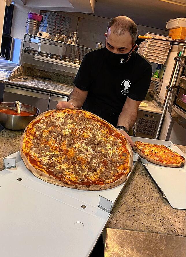 Geschäftsmitinhaber der Pizzeria &bdquo;Margarethen Schlössle&ldquo; Mario Di Sario verpackt Bestellungen.