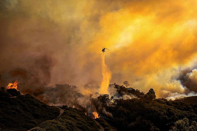 Ein Hubschrauber wirft im Stadtteil Pacific Palisades von Los Angeles Wasser auf das sich ausbreitende Palisades-Feuer.
