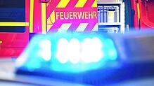 Ein Feuerwehrfahrzeug im Einsatz, davor ein Polizeiauto mit eingeschaltetem Blaulicht (Symbolbild). Ein Schlauchboot mit einem ...