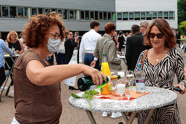 Mit Mund-Nasen-Schutz servieren die Helfer den Gästen der Abiturfeier am Gymansium am Hoptbühl die Getränke.