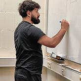 Mustafa Dagdeviren, Azubi bei der Firma Magnetbau Schramme im Deggenhausertal, erklärt seine Pneumatikschaltung an der Tafel.
