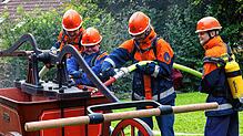 Mit Teamarbeit und sichtbarer Begeisterung befüllt die Jugendfeuerwehr die historische Handdruckspritze für den Spritzenwettbewerb.