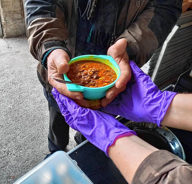 Ein Mann nimmt einen Teller heiße Suppe entgegen. Seit zwei Jahren kümmert sich der Verein Helfer mit Herz um Obdachlose und Bedürftige.