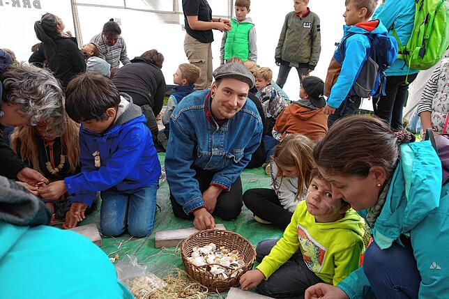 Moritz Kuhn, Archäologie-Student von der Uni Tübingen leitete Kinder im Mitmach-Zelt bei den Petersfelstagen dabei an, Steinzeitschmuck ...