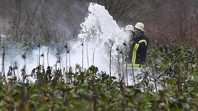 Feuerwehrleute löschen an der Unfallstelle bei Oberhausen-Rheinhausen die Trümmer.