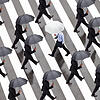 Menschen mit Regenschirmen gehen &ndash; jeder für sich &ndash; über einen Zebrastreifen. Die Arbeitswelt wird immer ...