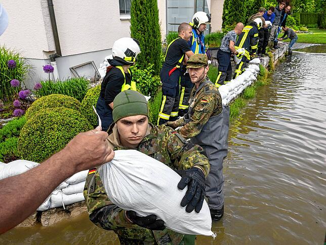 Bayern, Gundelfingen: Soldaten der Bundeswehr errichten gemeinsam mit zivilen Feuerwehrkräften eine Barriere aus Sandsäcken.