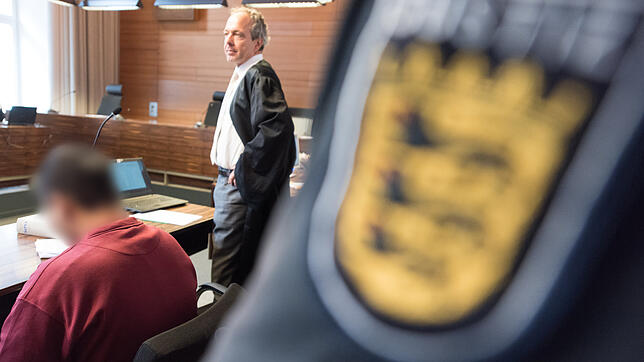 Der Angeklagte Hussein K. sitzt in Freiburg mit Handschellen im Landgericht im Gerichtssaal neben seinem Verteidiger Sebastian Glathe (r).