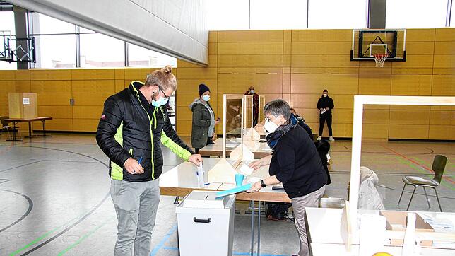 Ein Wähler gibt seine Stimme in der Rappensteinhalle ab. Rechts überprüft Stadträtin Manuela Pfister als Wahlhelferin die Stimmabgabe.