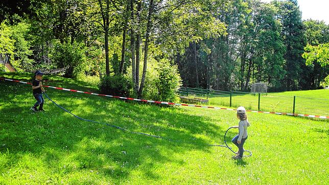 Der Garten wurde mithilfe von Absperrbändern für die Gruppen aufgeteilt. Hier spielen Sarah und Amando, sie sind beide drei Jahre alt.