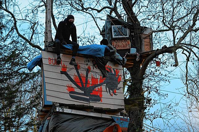 Einer der letzten verbliebenen Klimaaktivisten sitzt auf einem Haus auf Stelzen im sogenannten Fantasialand.