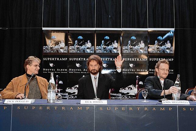 1997 mit Produzent Jack Douglas (links) und Saxofonist John Helliwell (rechts) bei einer Pressekonferenz zum Album „Some Things Never ...