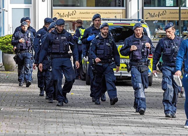 Einsatzkräfte der Polizei gehen am Sonntagmorgen am Tatort vorbei.