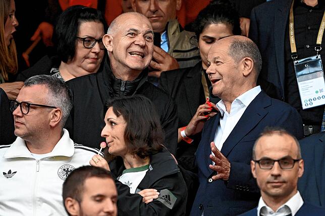 Bundeskanzler Olaf Scholz steht als Zuschauer auf der Tribüne neben DFB-Präsident Bernd Neuendorf.
