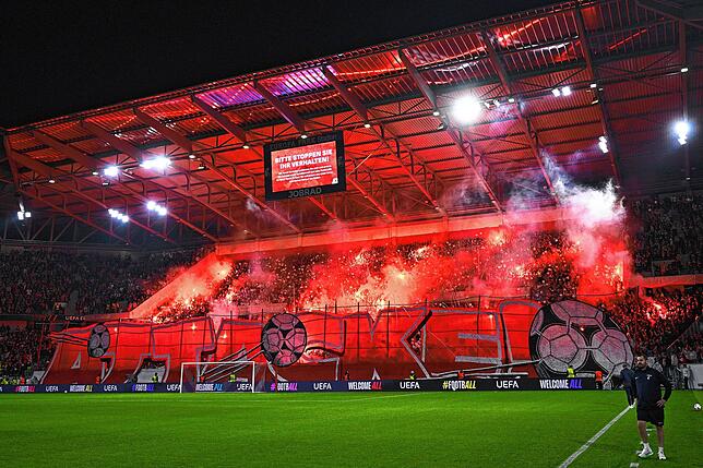 Freiburg-Fans brennen vor Spielbeginn während einer Choreographie rote Bengalos ab.