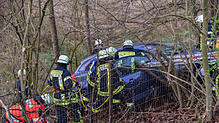Einsatzkräfte von Feuerwehr und Rotem Kreuz sind mit der Rettung der Beifahrerin beschäftigt. Aufgrund der Hanglage des Fahrzeugs ...