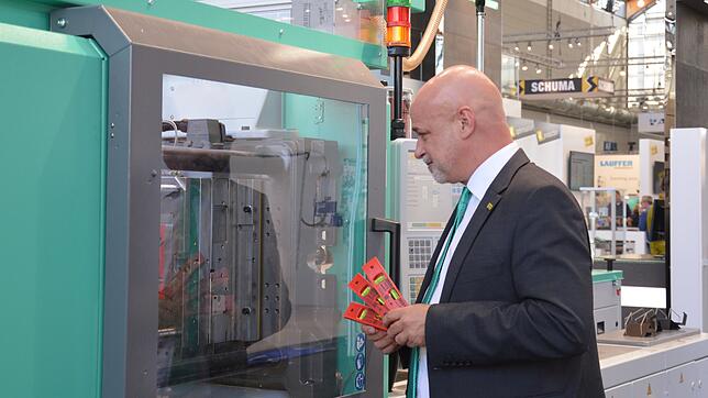 Arburg-Marketingchef Christoph Schumacher zeigt, wie eine Spritzgießmaschine eine Wasserwaage produziert.