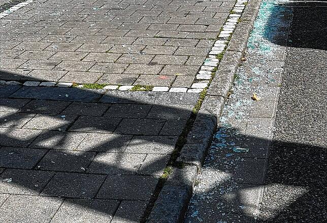 Bei der Explosion ist eine Fensterscheibe zerbrochen. Die Glasscherben liegen danach auf dem Gehweg und der Straße.